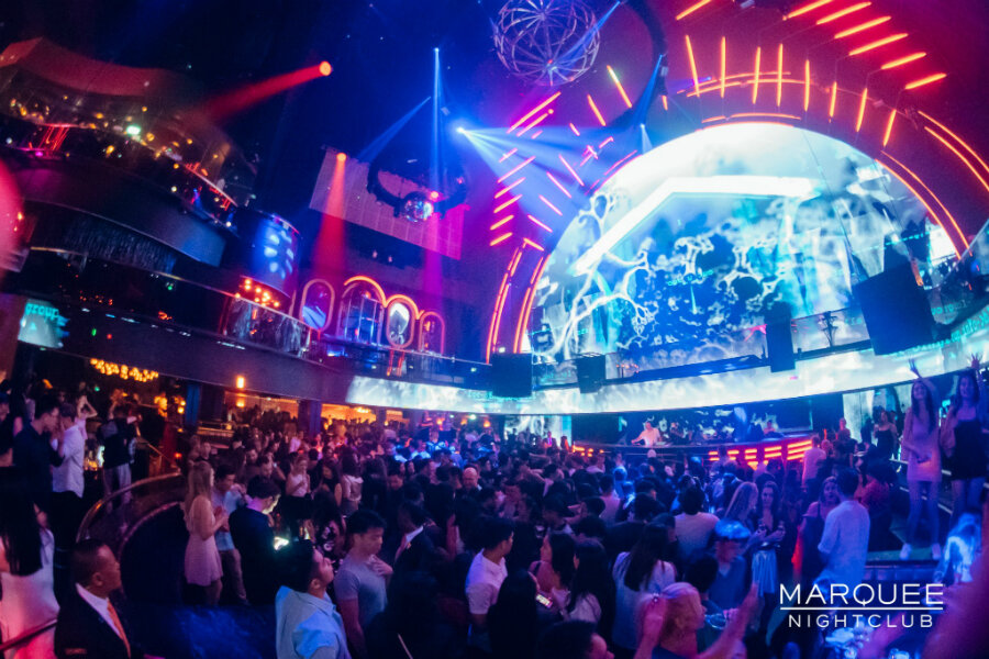 La pista de MARQUEE con luces de colores y gente bailando.