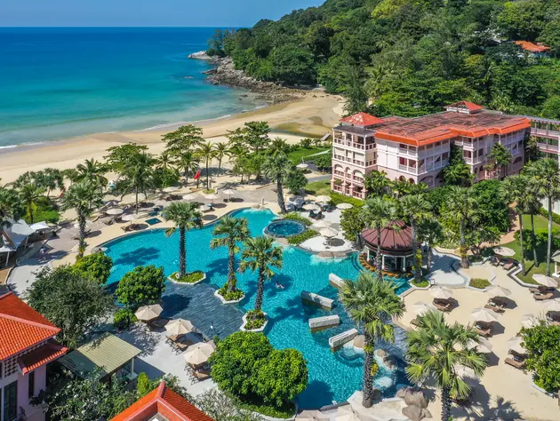 Un resort frente a la playa en Phuket, rodeado de palmeras y piscinas.